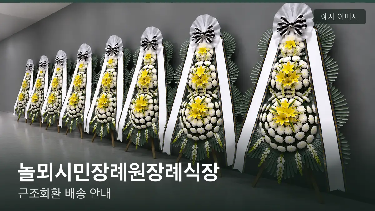 놀뫼시민장례원장례식장 근조화환 예시 이미지 — 흰 국화 3단 근조화환이 벽을 따라 나란히 놓인 모습