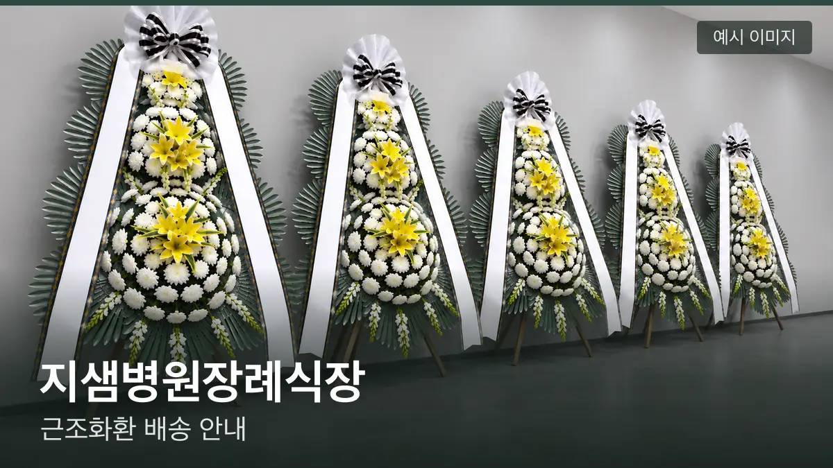 지샘병원장례식장 근조화환 예시 이미지 — 흰 국화 3단 근조화환이 벽을 따라 나란히 놓인 모습