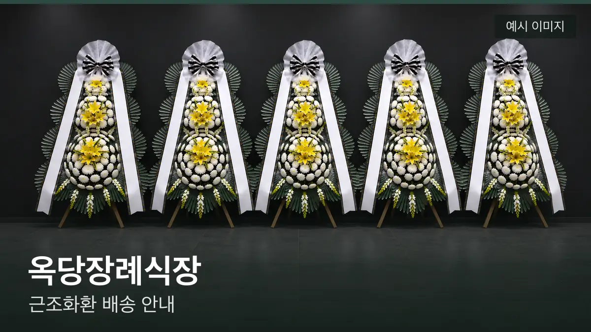 옥당장례식장 근조화환 예시 이미지 — 흰 국화 3단 근조화환이 벽을 따라 나란히 놓인 모습